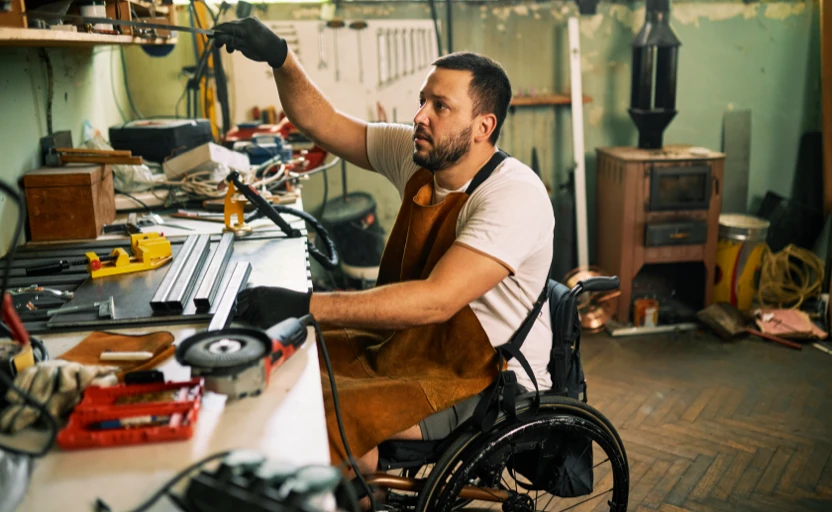 man in wheelchair working at work bench.