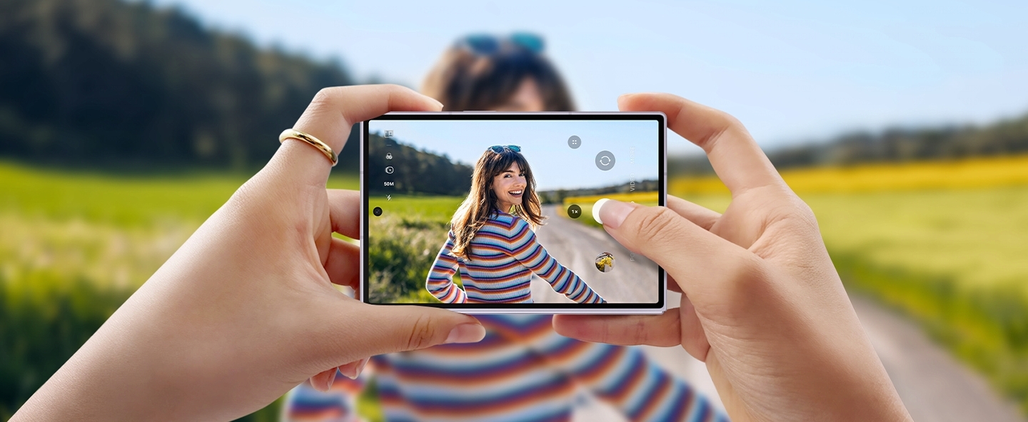 Mit einem Galaxy Z Fold8 wird eine Person vor einer malerischen Kulisse fotografiert. Das Gerät wird zusammengeklappt und horizontal gehalten. Das Foto ist auf dem Frontdisplay zu sehen.
