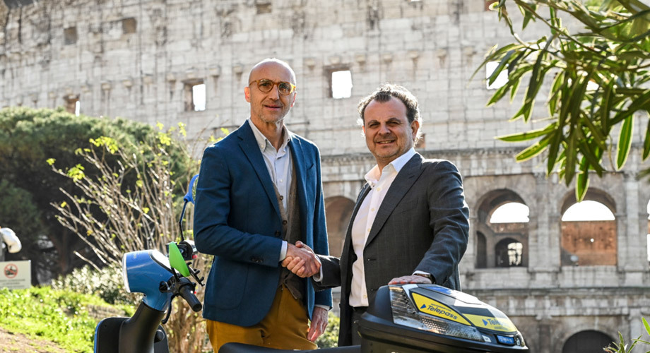 Partnership Telepass e Cooltra. Nella foto: da destra Aldo Agostinelli di Telepass ed Enrico Pascarella di Cooltra posano dinanzi al Colosseo (Roma), accanto a un motorino Cooltra brandizzato Telepass.