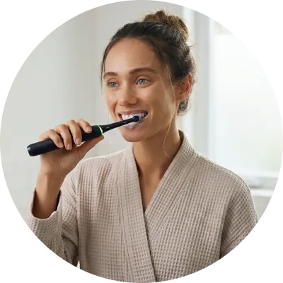Frau putzt Zähne mit Oral-B iO Elektrozahnbürste – konsequente tägliche Mundhygiene als wirksame Prävention gegen Zahnfleischerkrankungen