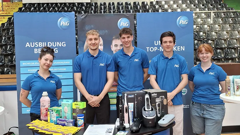 Teammitglieder an einem P&G-Stand präsentieren Produkte auf einer Karrieremesse