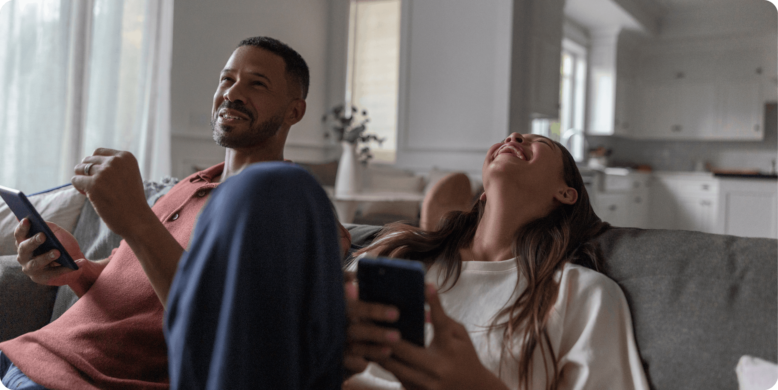 Two young adults relaxing and smiling while browsing on their smartphones, representing the ease and accessibility of managing payments with Affirm.