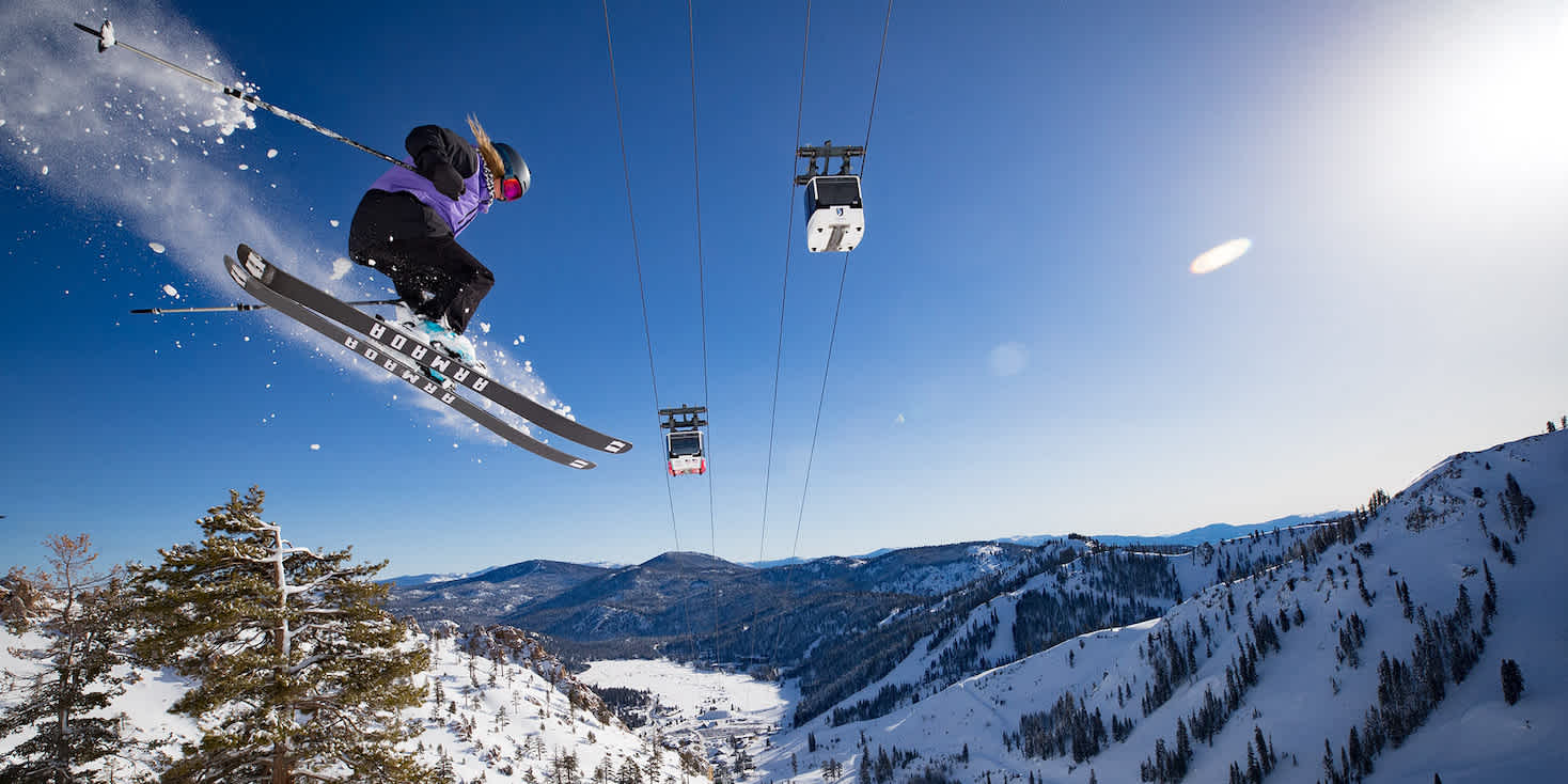 Action shot of a skier in mid-air with powder flying and ski lift chairs above