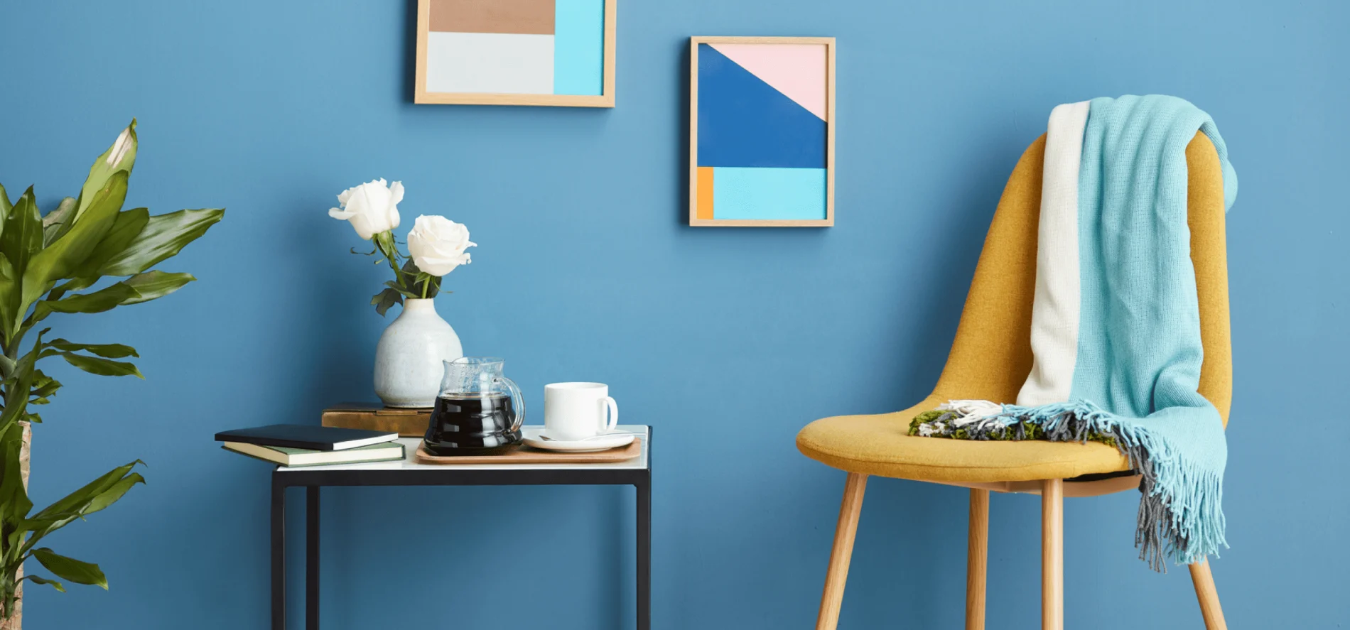 image of an end table with coffee and flower vase with a chair and plant on either side