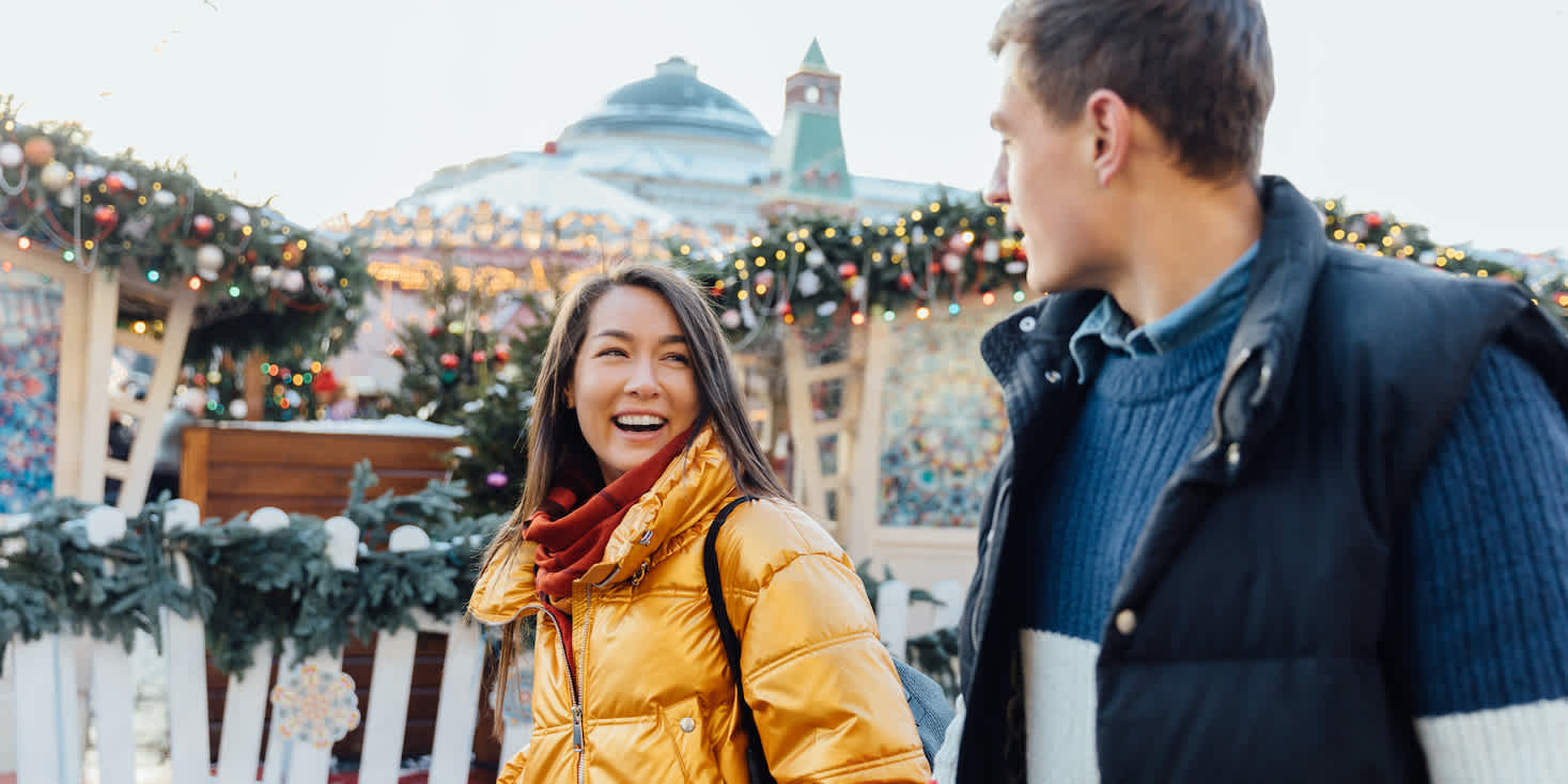 Couple out walking, with holiday lights and decorations in the background