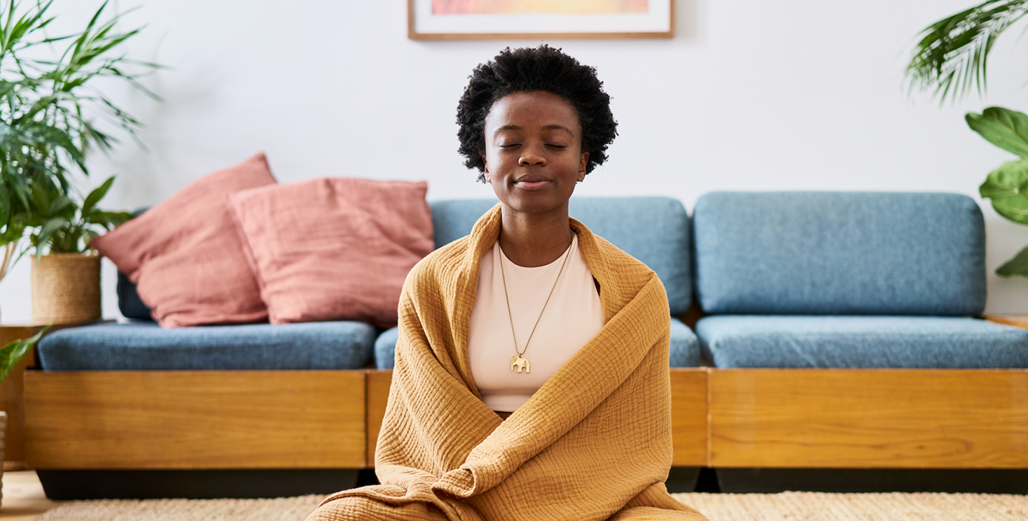 Young woman sitting meditatively wrapped in comfortable shawl