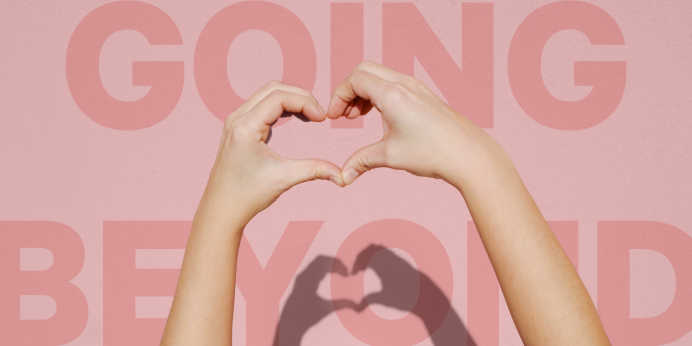 Shot of a pair of hands making a heart, with "Going Beyond" message in the background