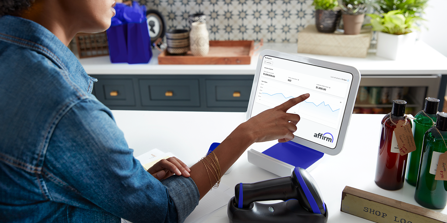 Over-shoulder shot of a woman business owner as she is checking her Affirm dashboard on a tablet.