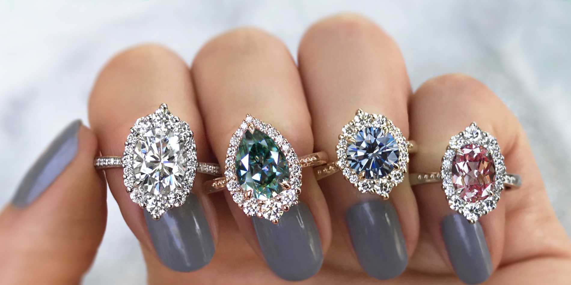 Close-up of custom engagement rings, each on a different finger of a woman's hand.