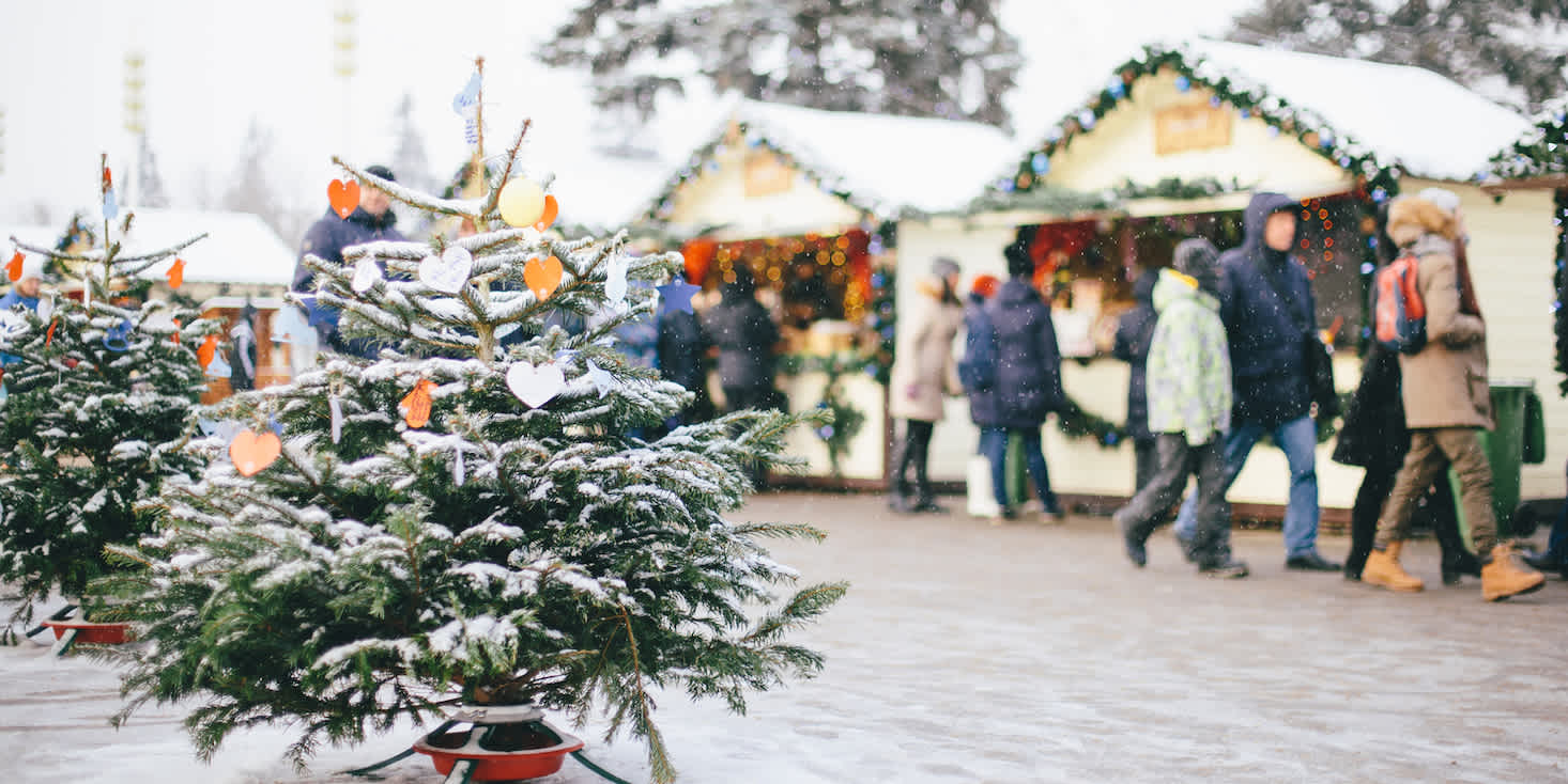 Snowy outdoor holiday shopping plaza, with dozens of shoppers in winter gear