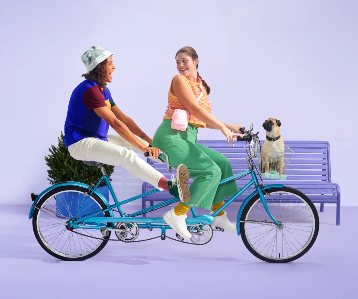 Image of two people on a double bike with a pug dog in the basket