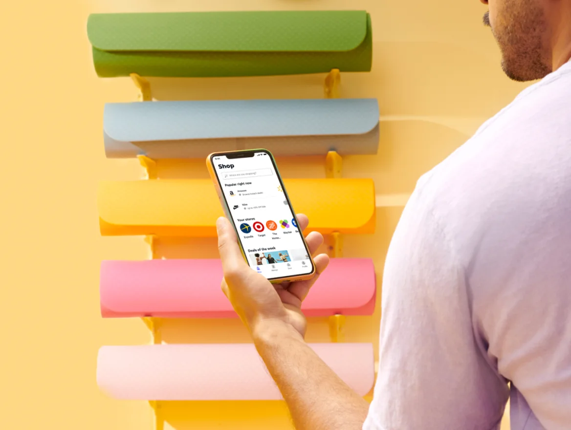 Image of person looking at their smartphone with colorful shelves in the background