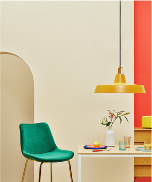 Image of green chair next to set table and gold lamp hanging from ceiling. 