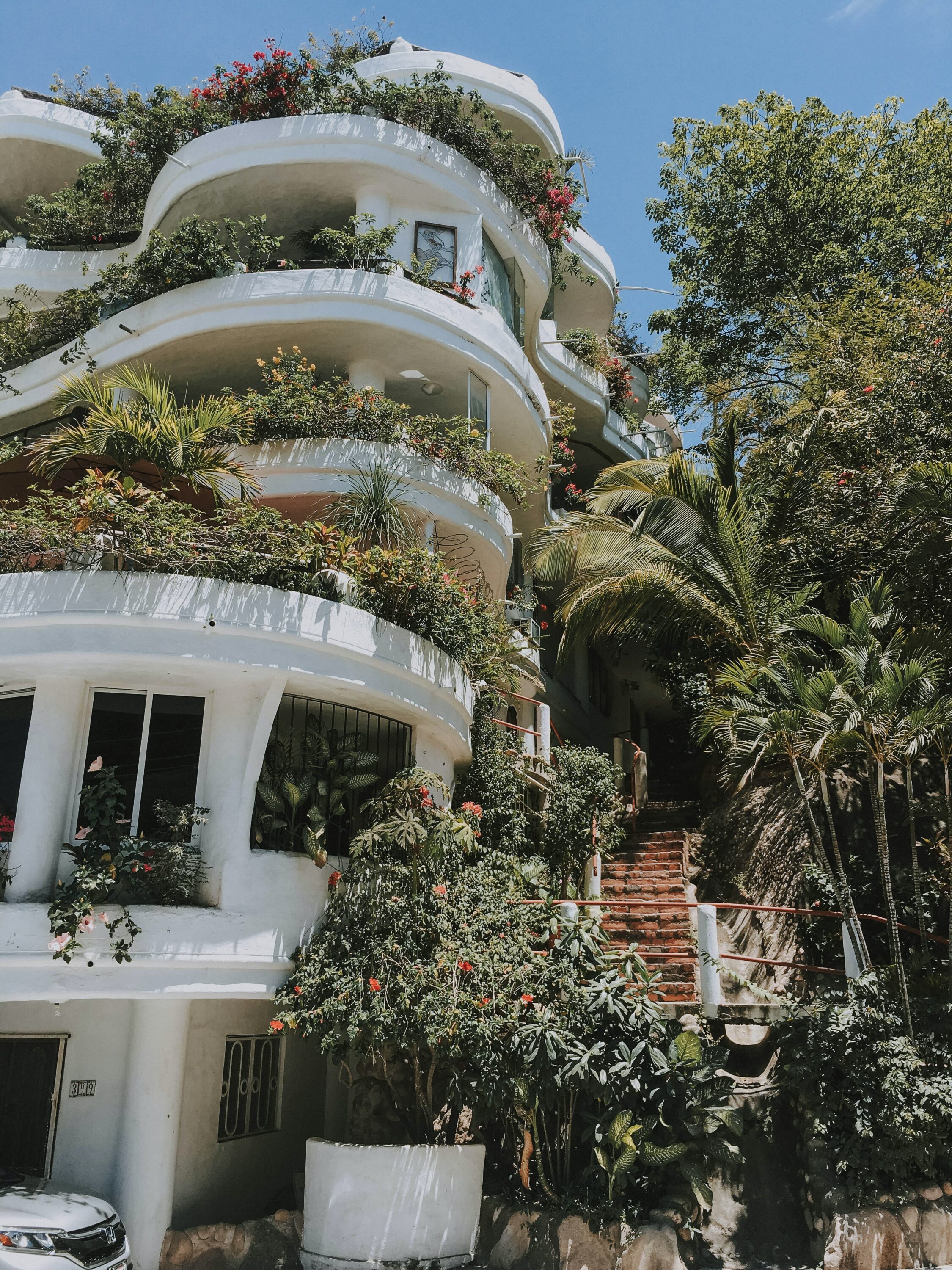 white building with lots of vegetation on the balconies