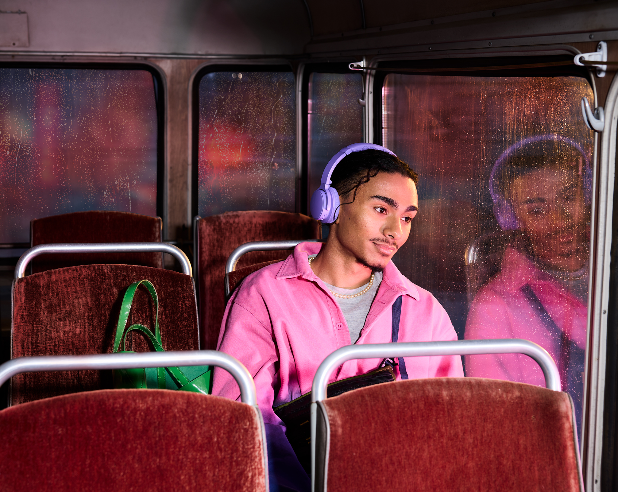 En mand med høretelefoner på en bus, der kigger ud af vinduet. 