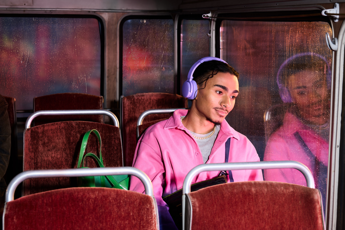 Mand i en bus med høretelefoner, mens han kigger ud.
