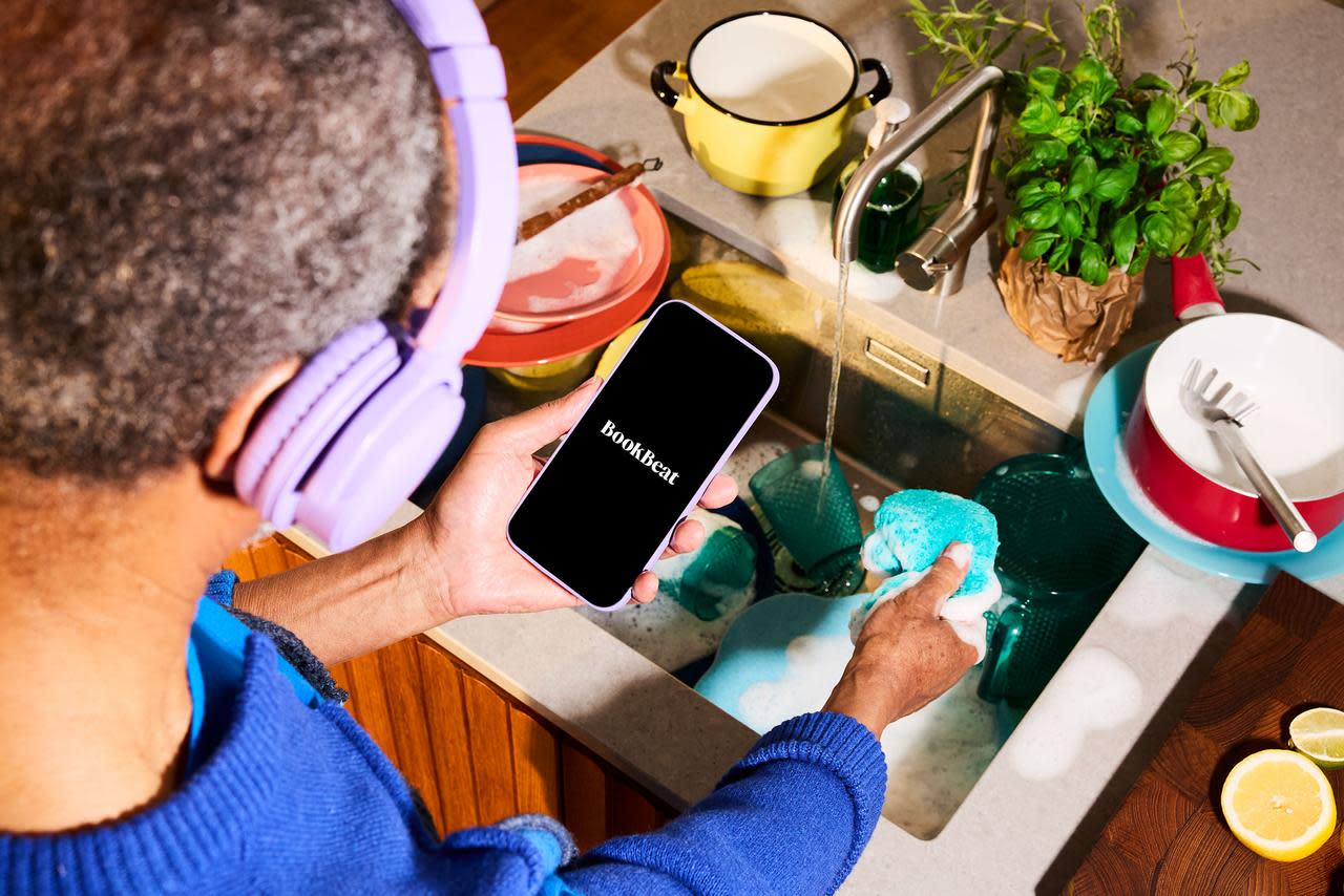Osoba zmywająca naczynia i słuchająca audiobooka w aplikacji BookBeat
