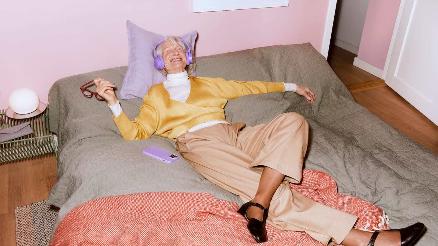 A female lying in bed and enjoying an audiobook. 