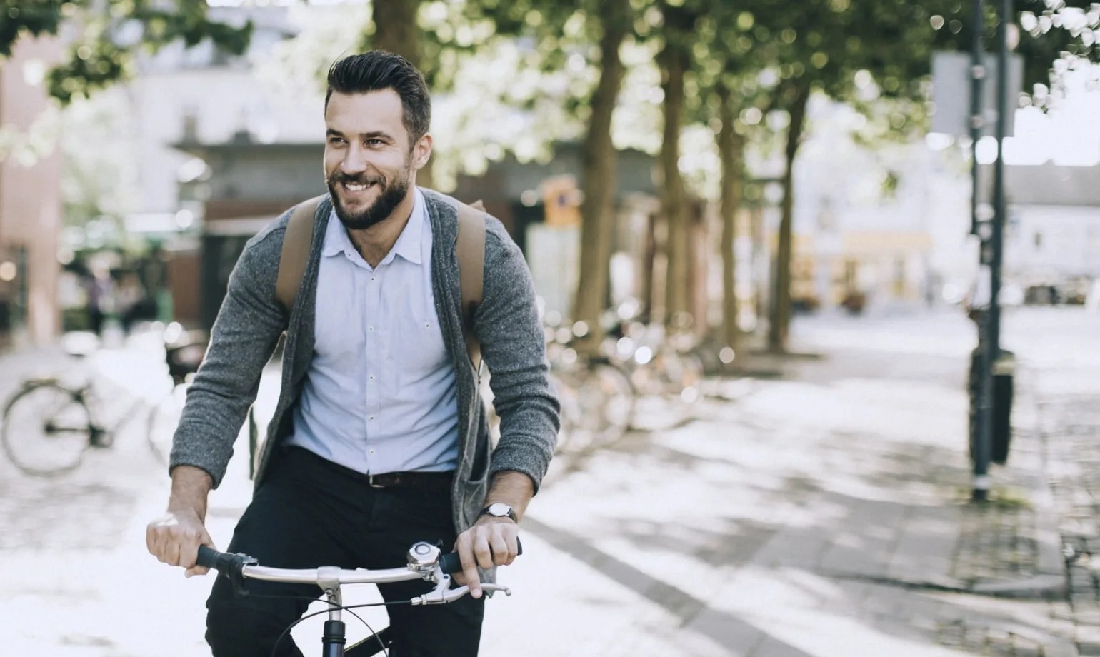 Un homme avec une barbe et une coiffure minimalistes fait du vélo dans les rues.