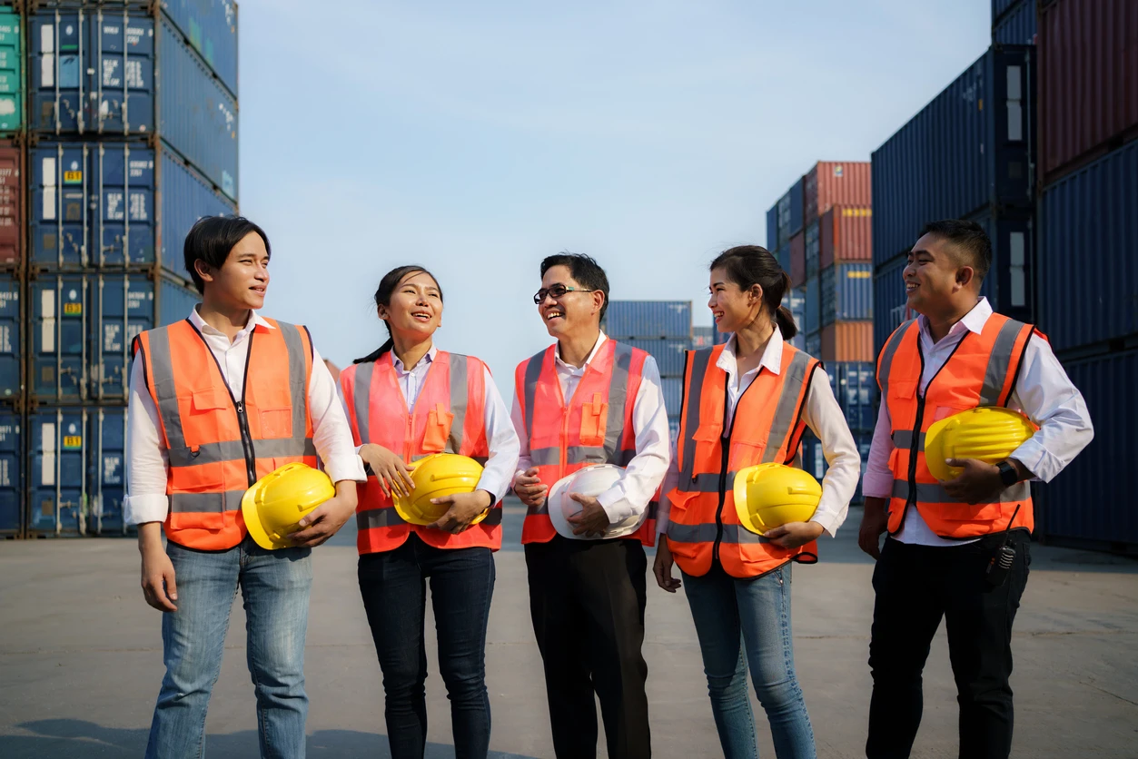 Asian foreman and staff resting and talking together in the container depot terminal after work in evening. stock photo