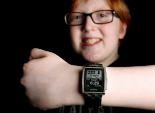 boy with type 1 diabetes smiling at his watch using CGMS (continuous glucose monitoring)