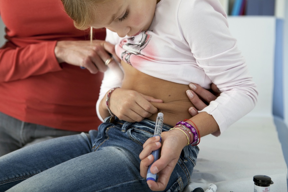 Young child with type 1 diabetes mellitus learning how to inject insulin
