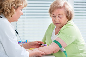 Nurse conducts Hb A1c blood test on elderly woman with type 2 diabetes