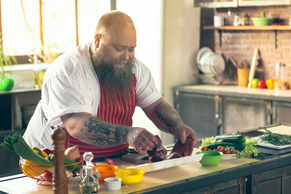 Overweight man with diabetes type 2 diabetes cooking meat and vegetables