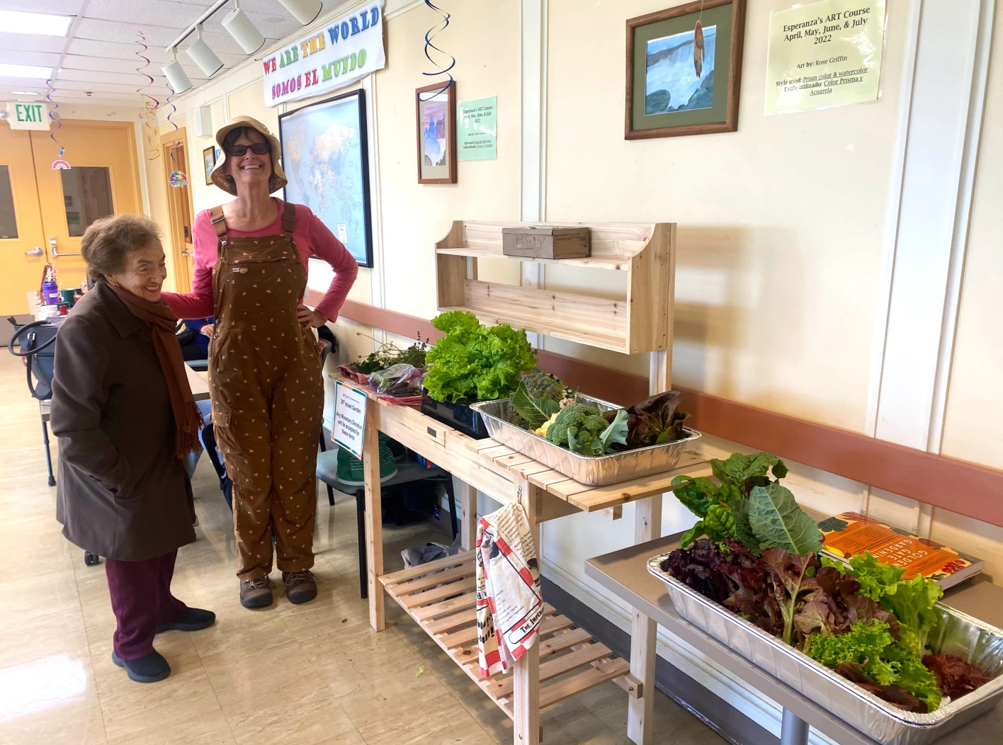 Senior and staff stand by community garden vegetables