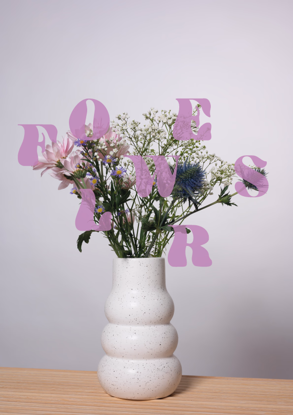Kukkakimppu pulleassa valkoisessa maljakossa, 'FLOWERS' leikkisin liiloin kirjaimin.