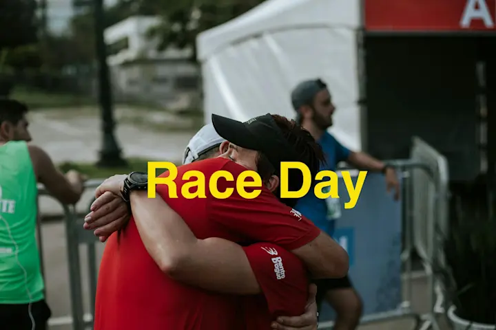 Paavo Nurmi Marathon Race Day Celebration: Two Runners Embracing At Finish Line With 'Race Day' Text Overlay In Yellow, Event Tents Visible In Background.