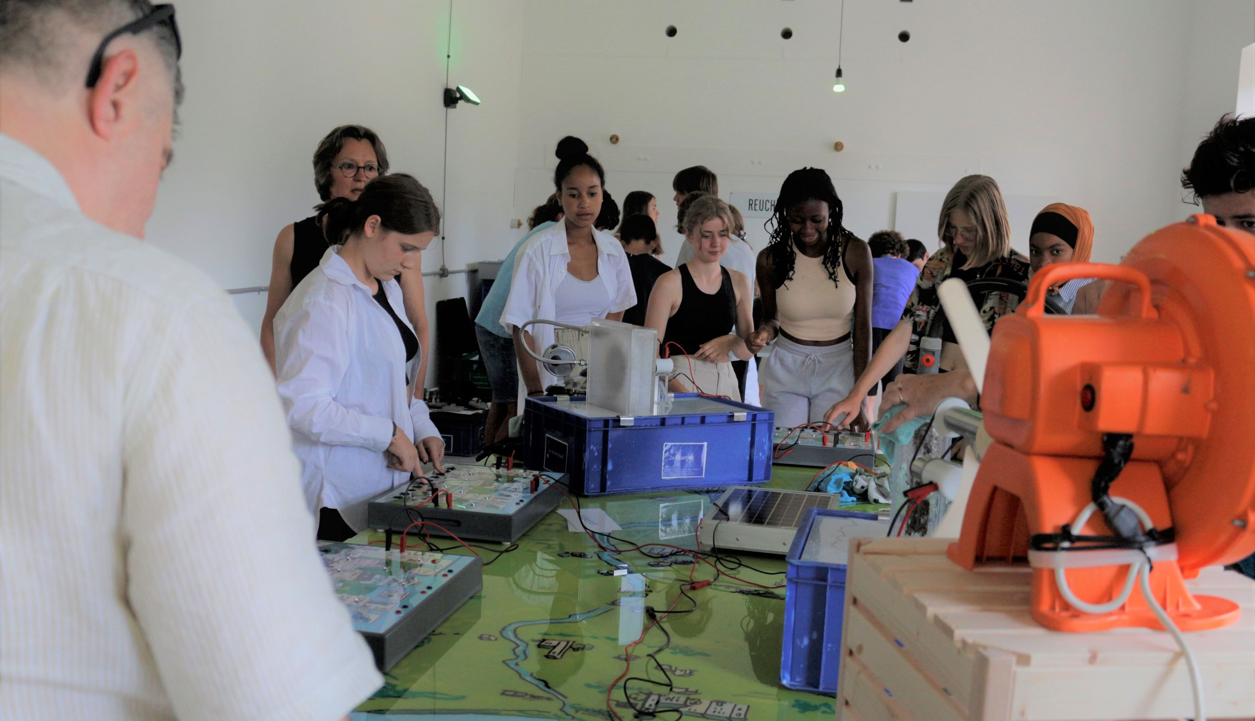 Gli allievi sono seduti a un tavolo con un insegnante e affrontano temi relativi all’energia e alla transizione energetica.