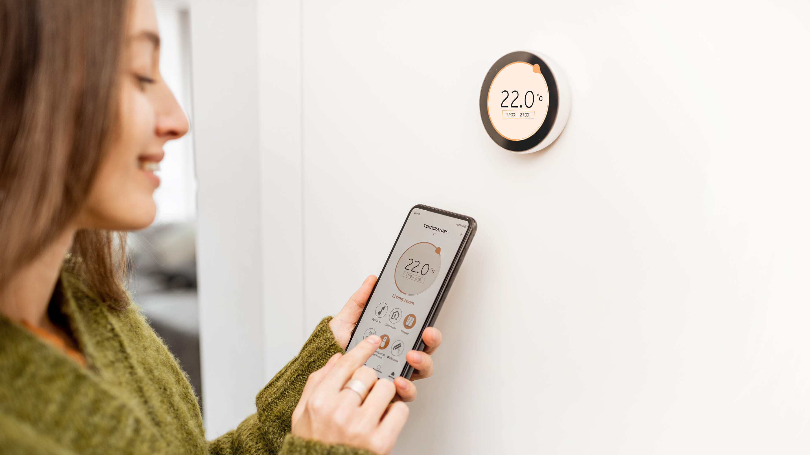 Una donna controlla il calore nella sua casa con il suo telefono cellulare.