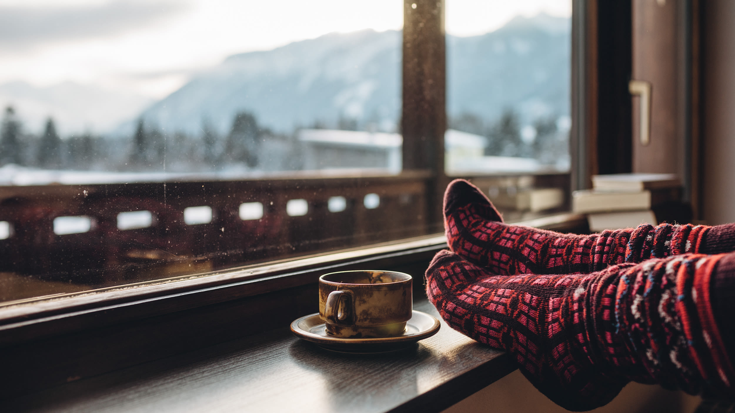 Pieds en chaussettes épaisses et une tasse de café sur le rebord de la fenêtre