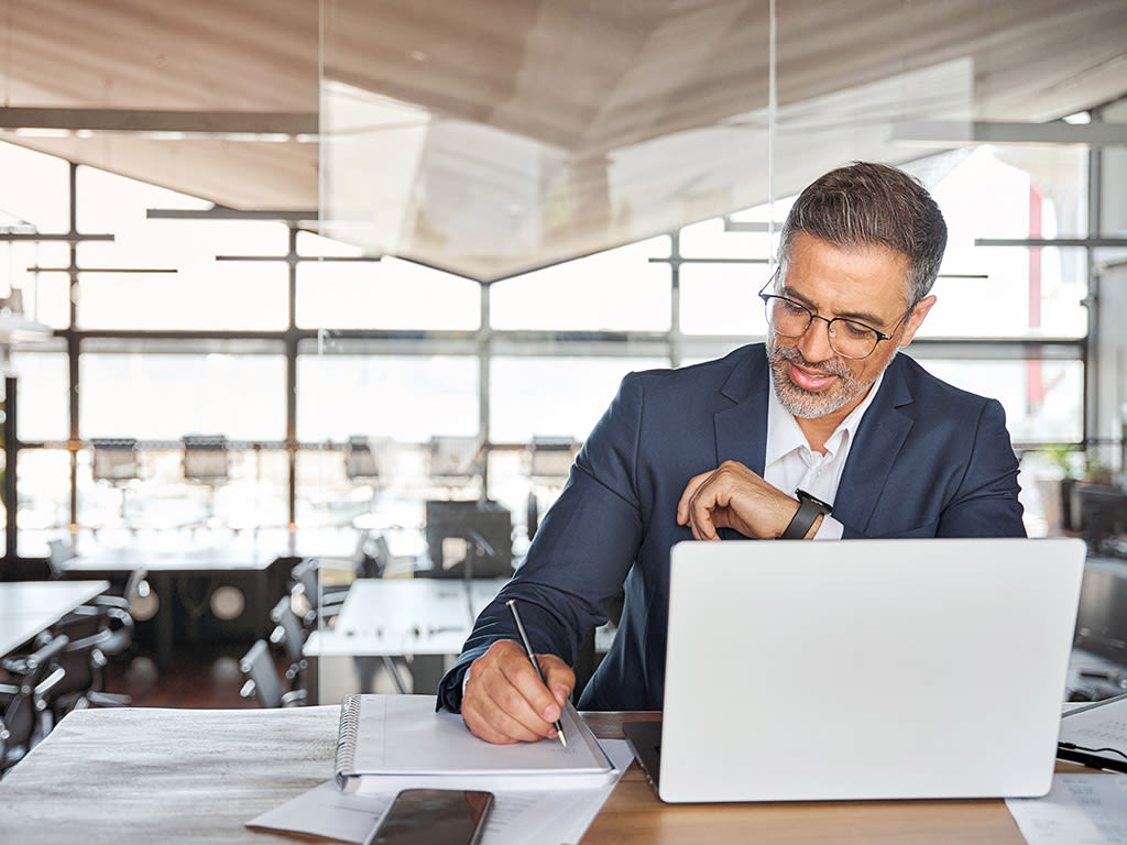 Un homme d'affaires avec un ordinateur portable prend des notes 