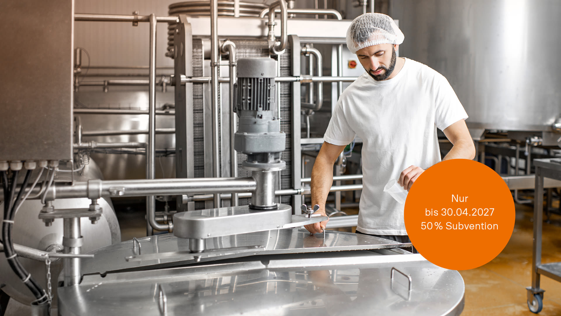 Arbeiters in Uniform in der Nähe eines Edelstahltanks in einem Unternehmen der Lebensmittelindustrie