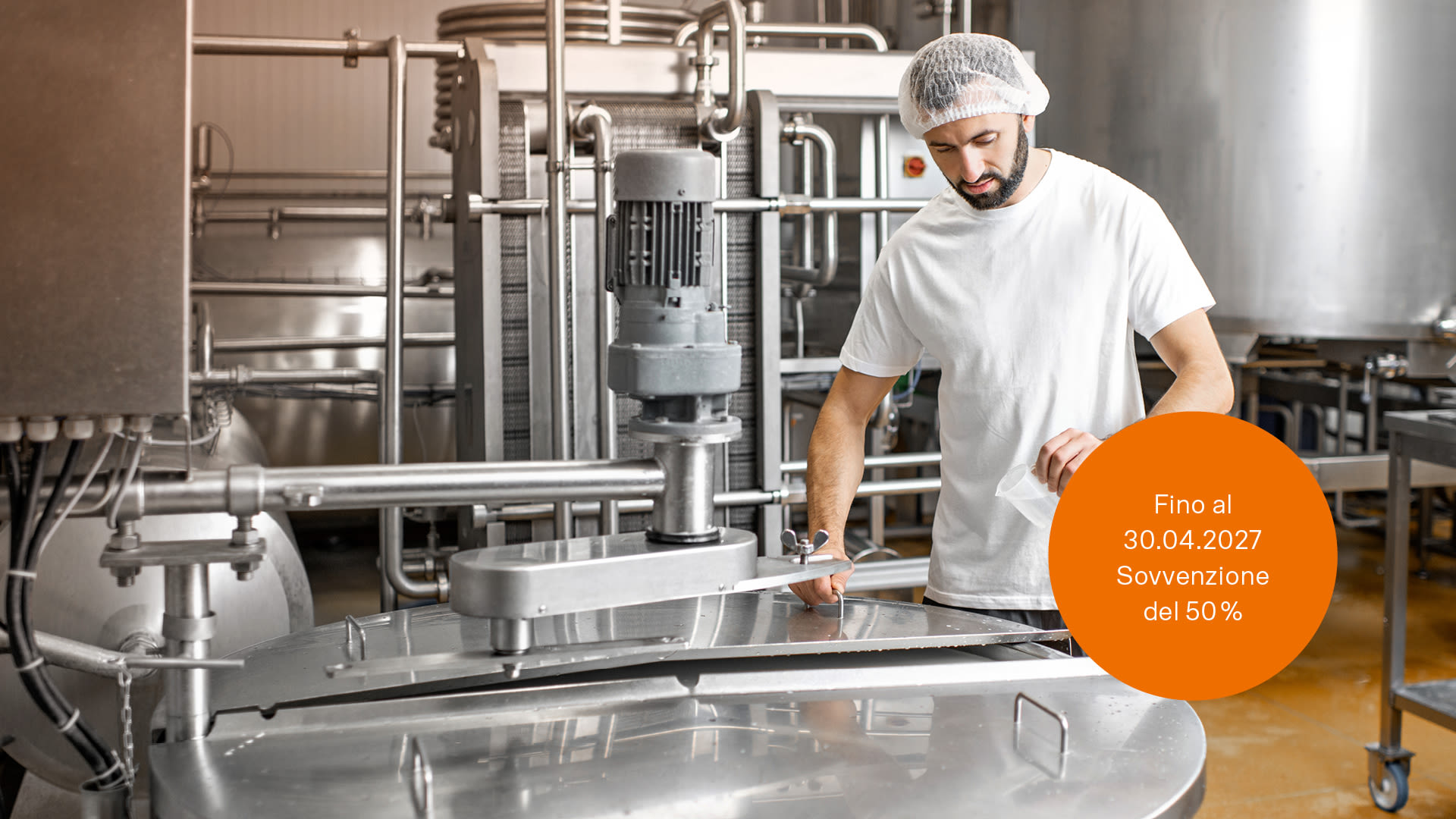 Lavoratore in uniforme vicino a un serbatoio di acciaio inossidabile in un'azienda del settore alimentare
