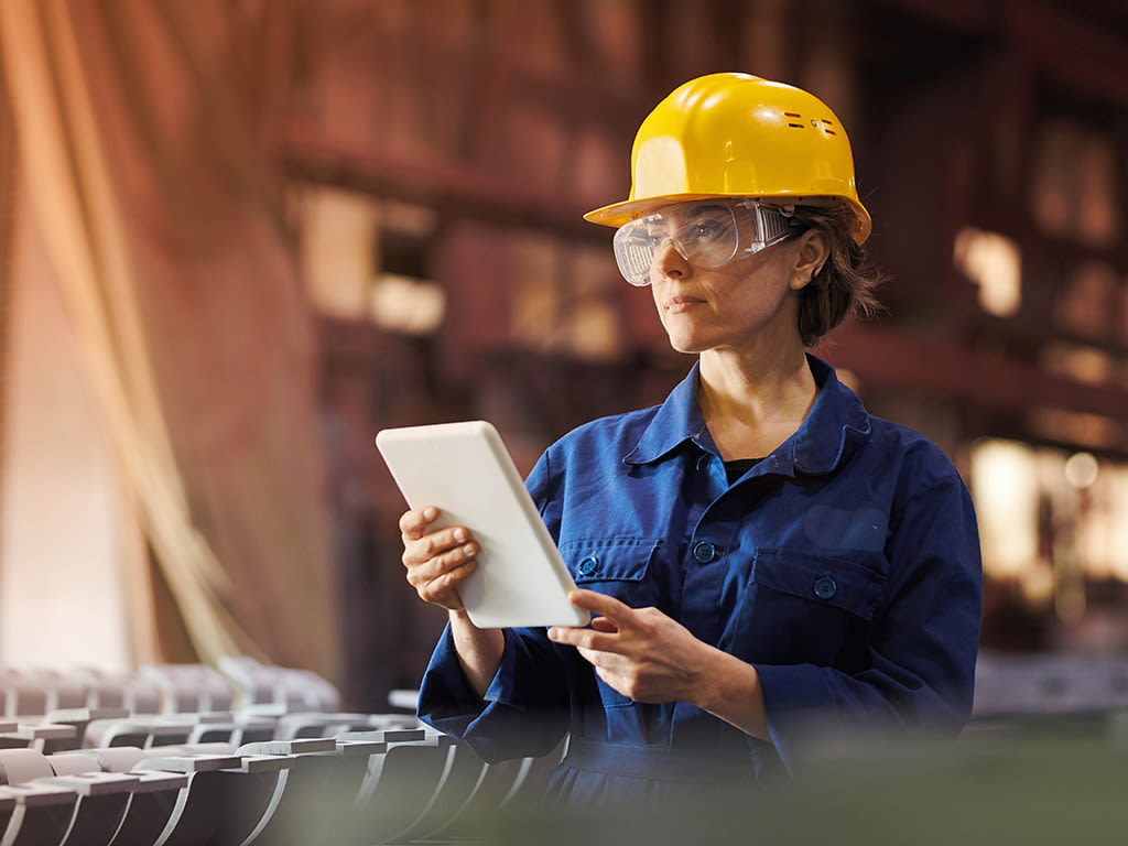 Femme professionnelle dans une entreprise industrielle avec une tablette et un casque.