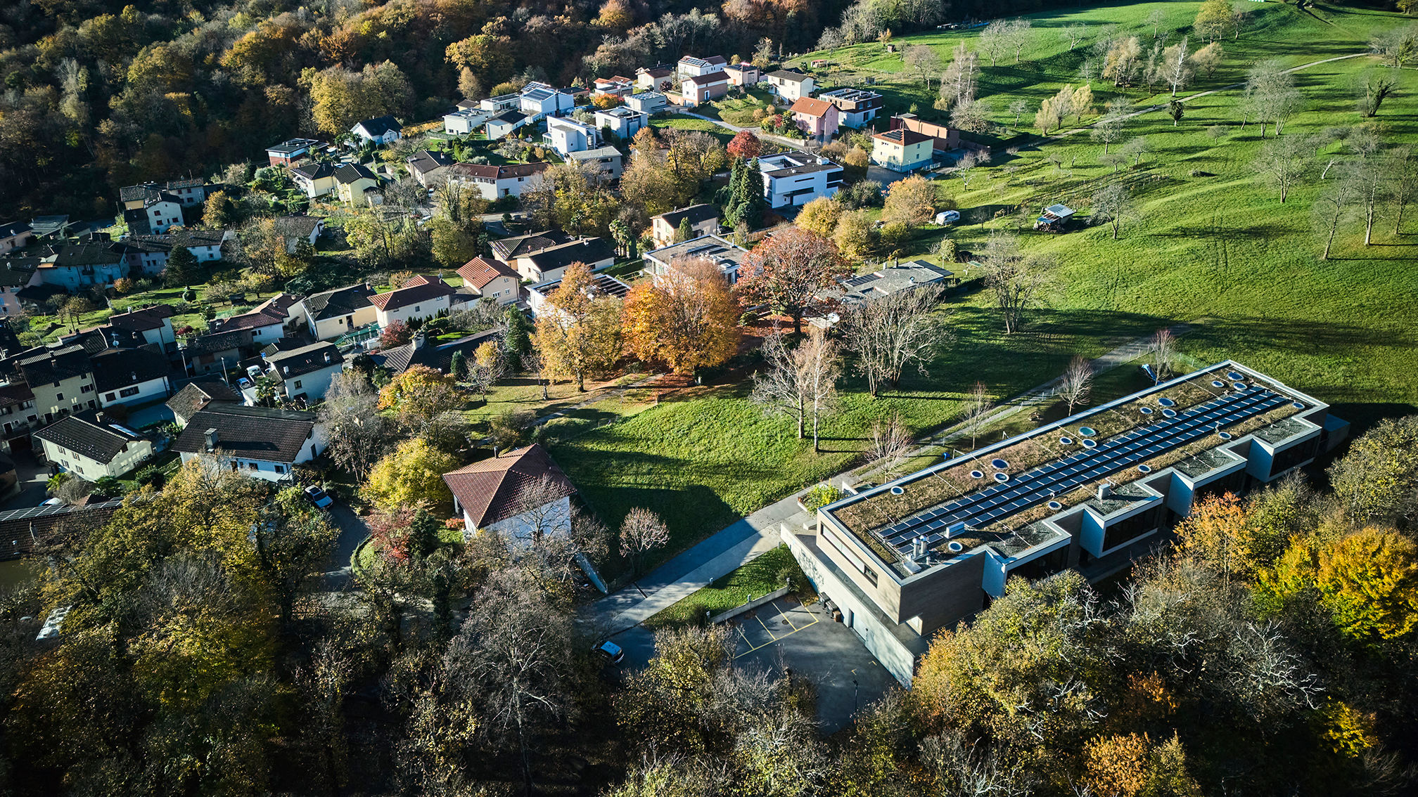 Vista aerea di Lugaggia con la scuola, il cui tetto è coperto di pannelli solari, in primo piano