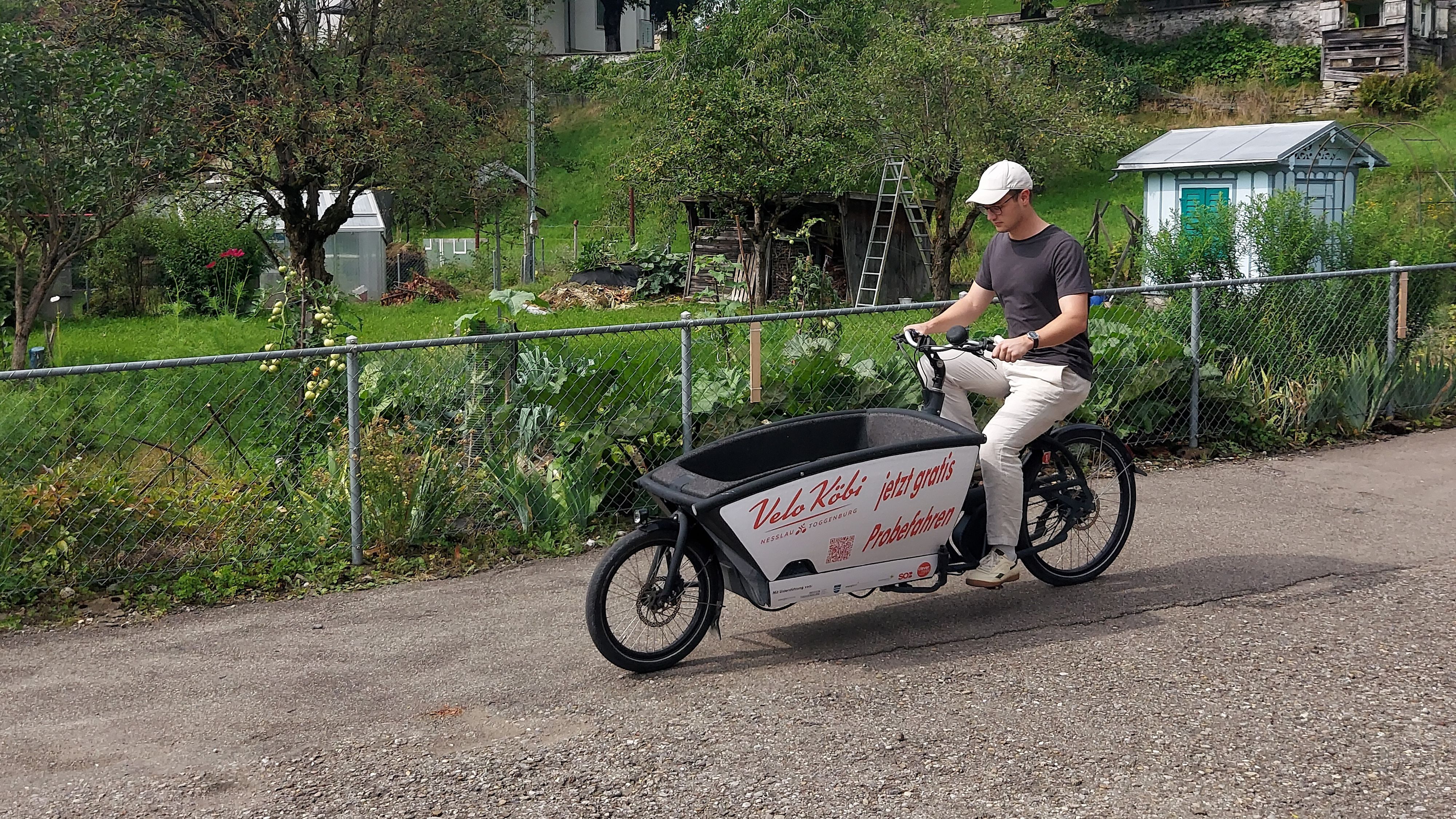 Un homme circule sur une route avec un vélo cargo.
