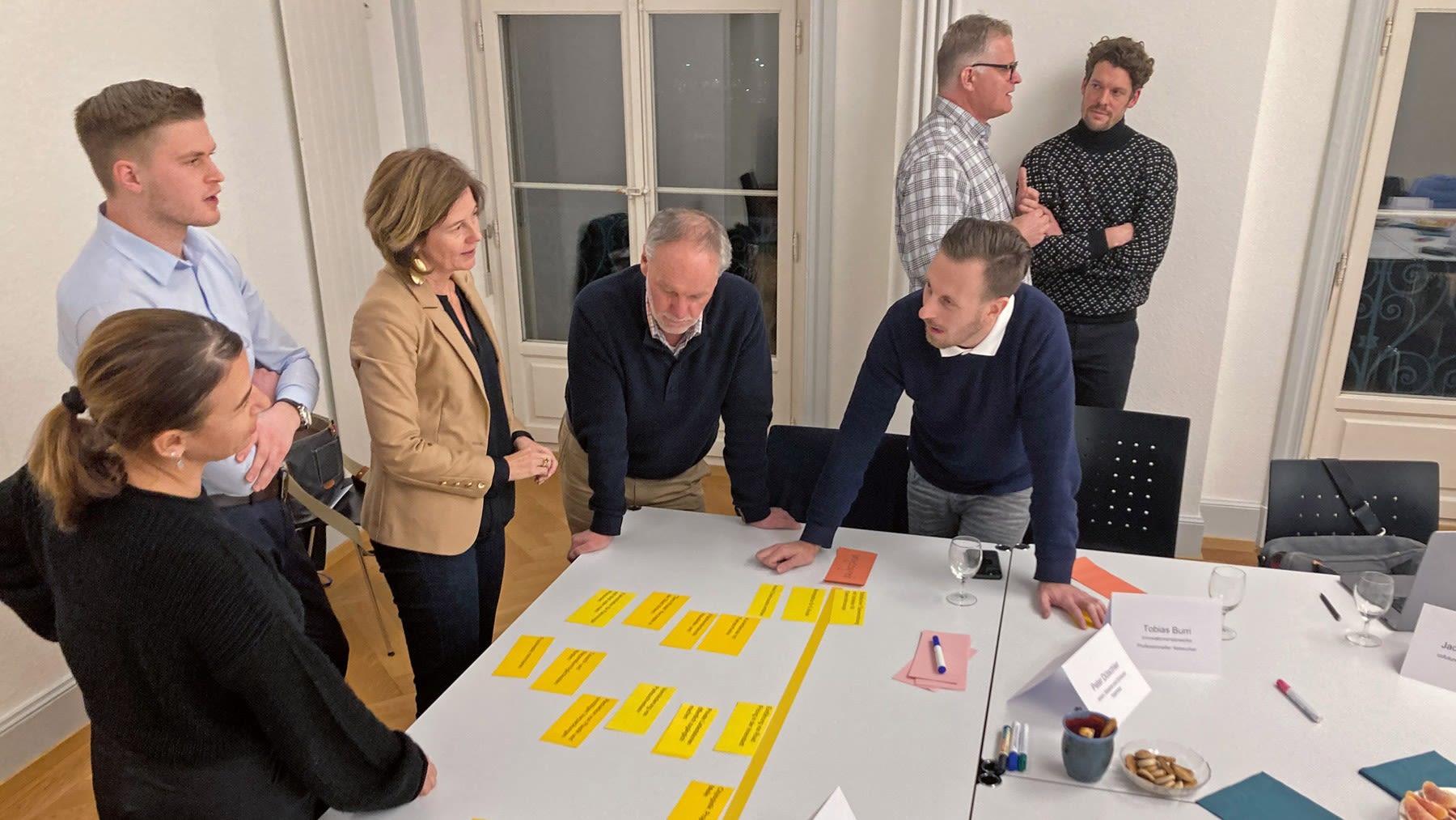 Plusieurs personnes discutent ensemble. Sur la table se trouvent des post-it avec des inscriptions.