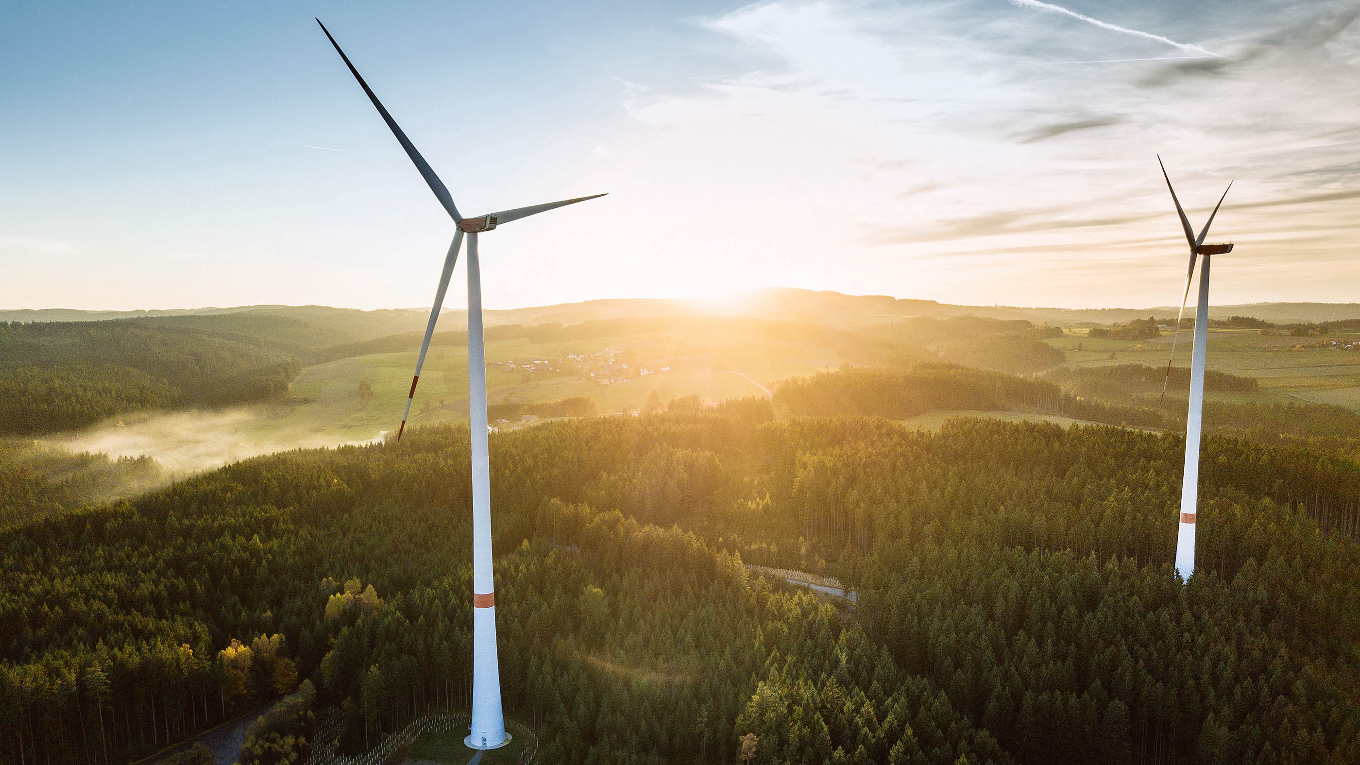 Due turbine eoliche all'alba nella natura.