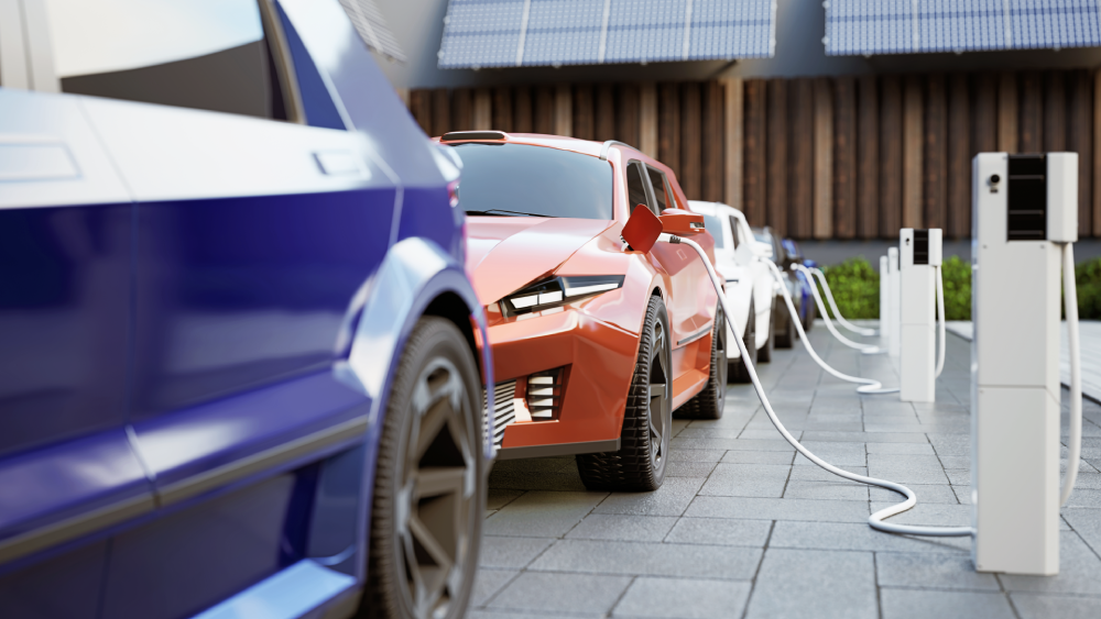 Plusieurs voitures rechargent les unes devant les autres sur un parking privé d'un petit immeuble moderne