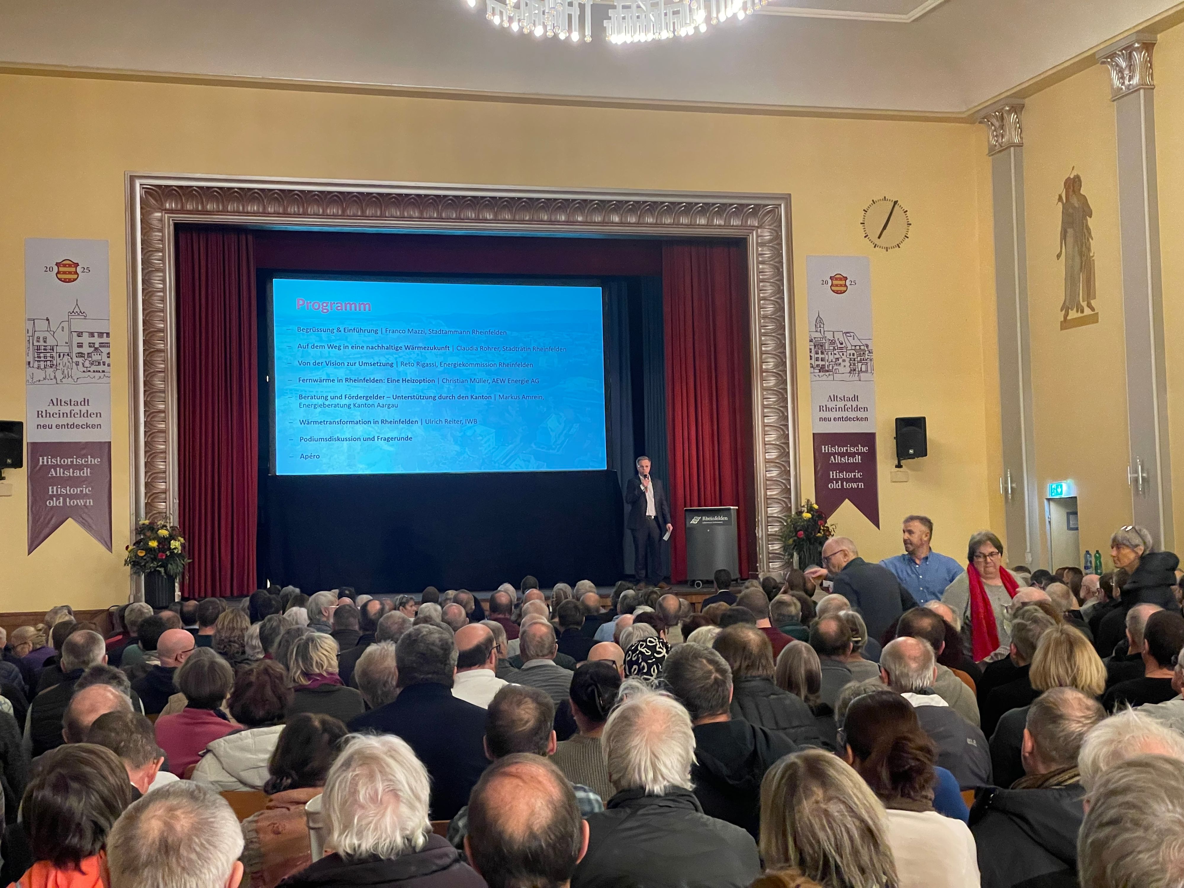 Informationsveranstaltung in Rheinfelden mit Publikum und Referent auf der Bühne.