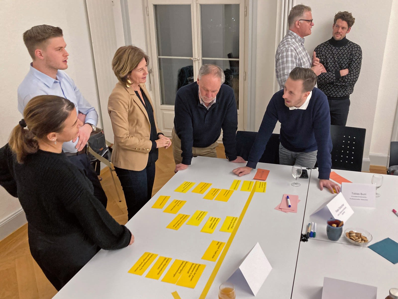 Plusieurs personnes discutent ensemble. Sur la table se trouvent des post-it avec des inscriptions.