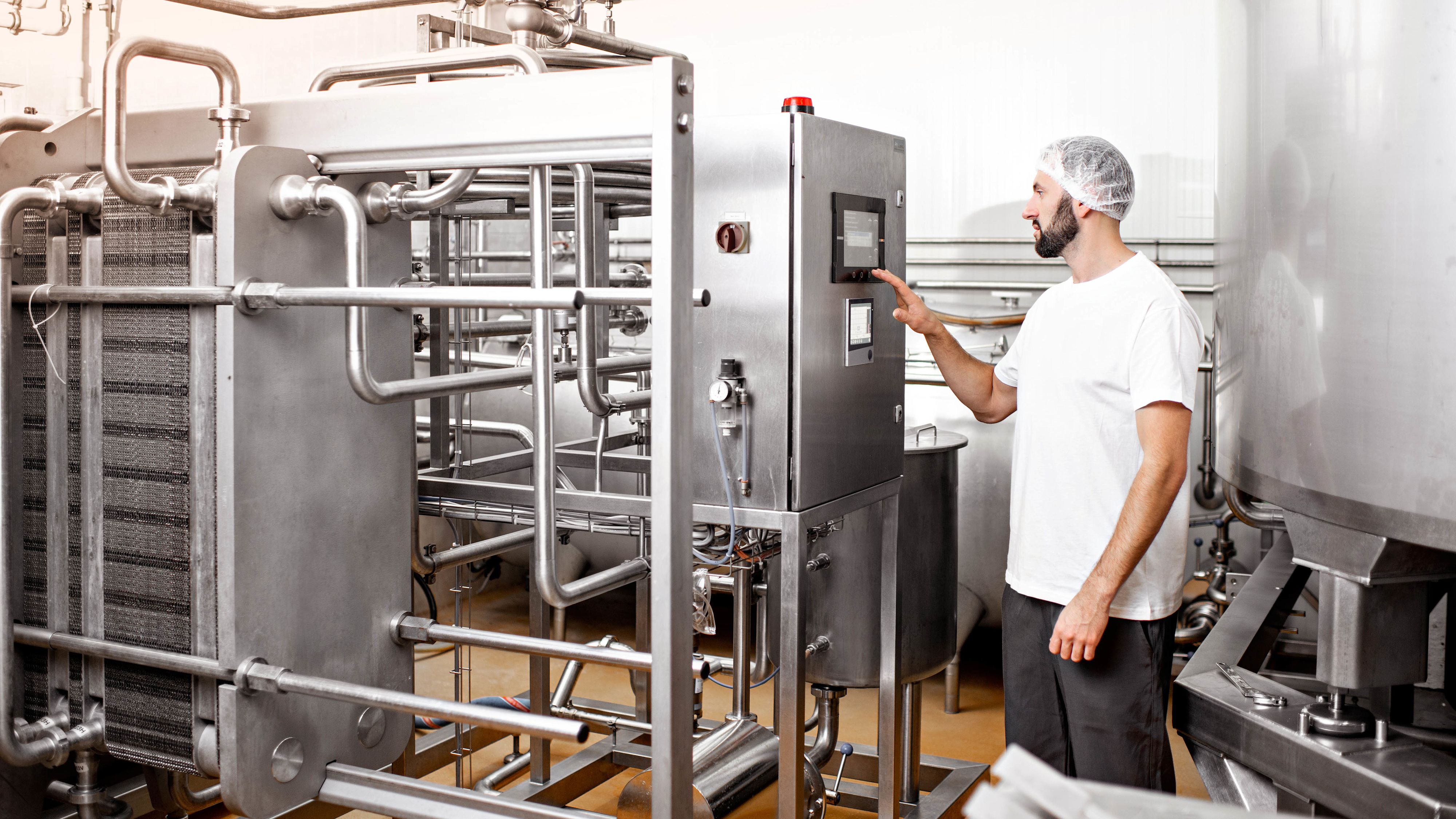 Un ouvrier en uniforme manie une machine dans une entreprise de l'industrie alimentaire