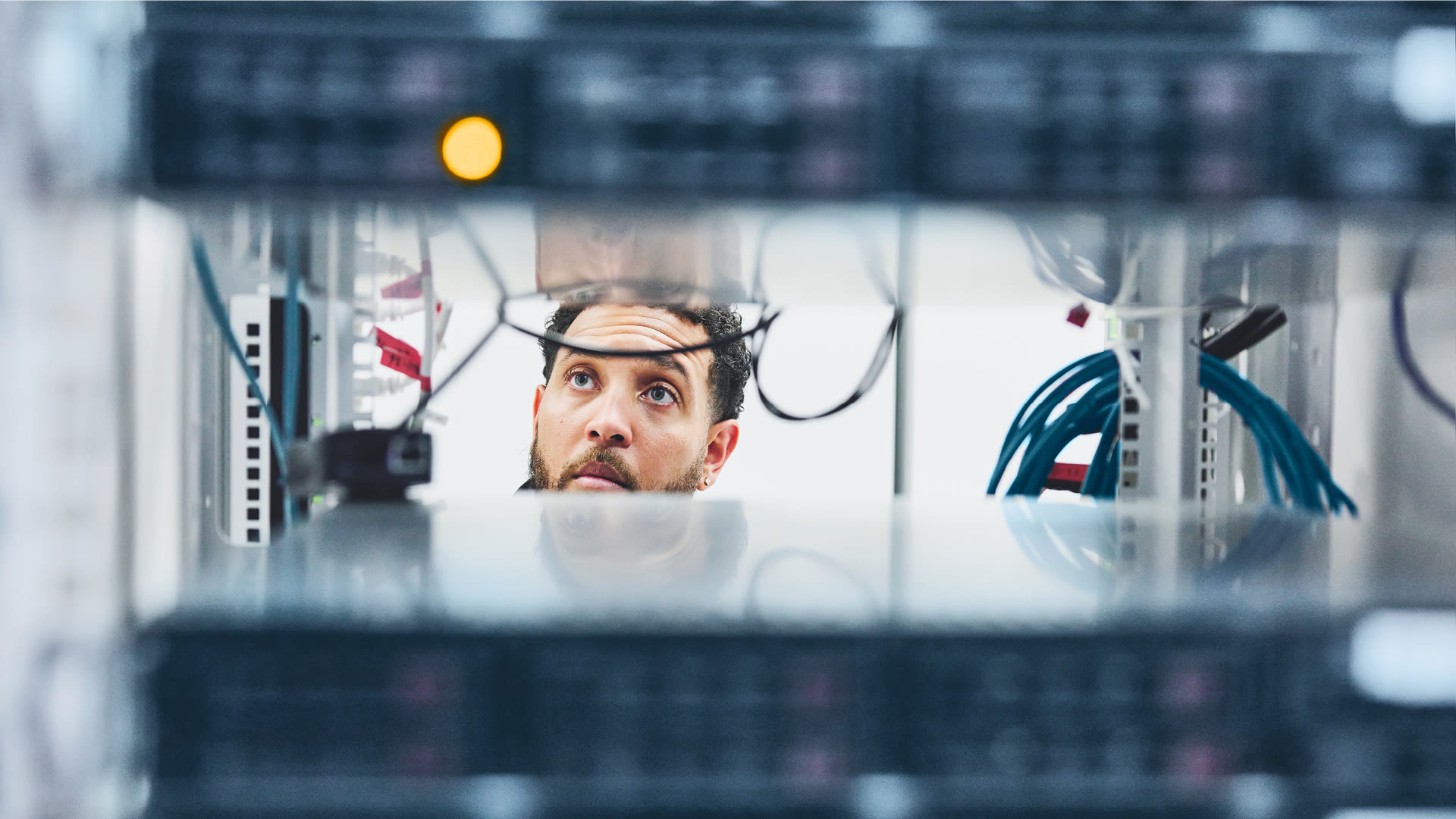 Un collaboratore controlla il cablaggio all’interno di un rack di server in un centro dati.