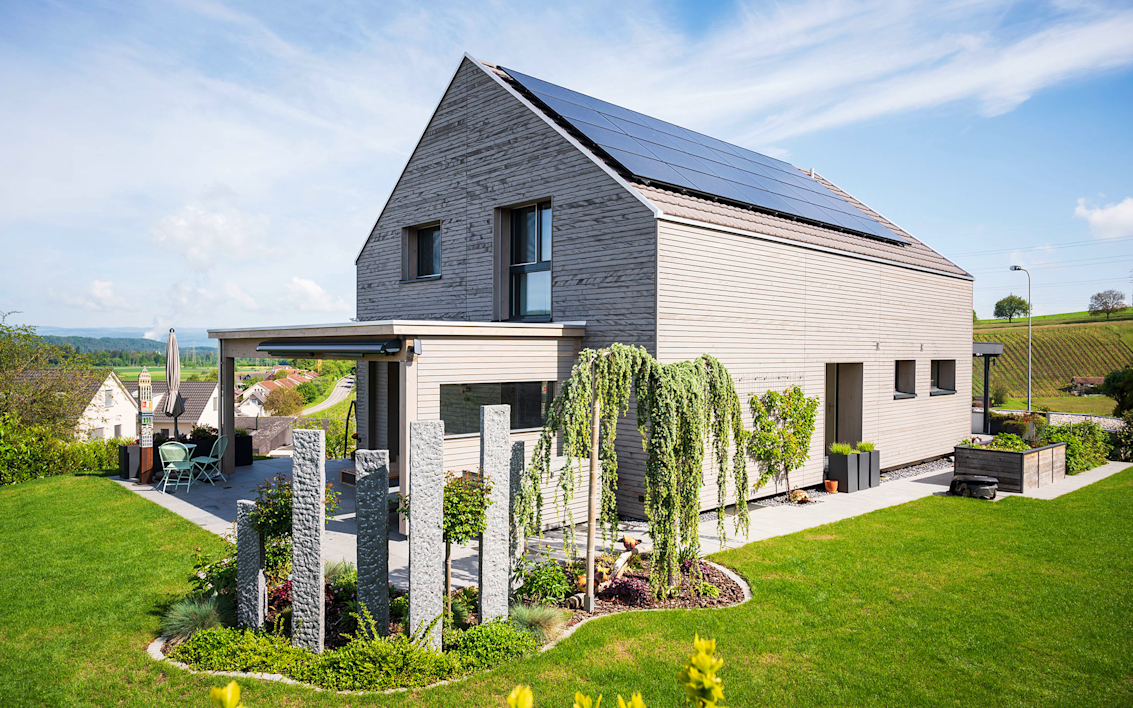 Une maison individuelle moderne avec un jardin et des panneaux solaires sur le toit