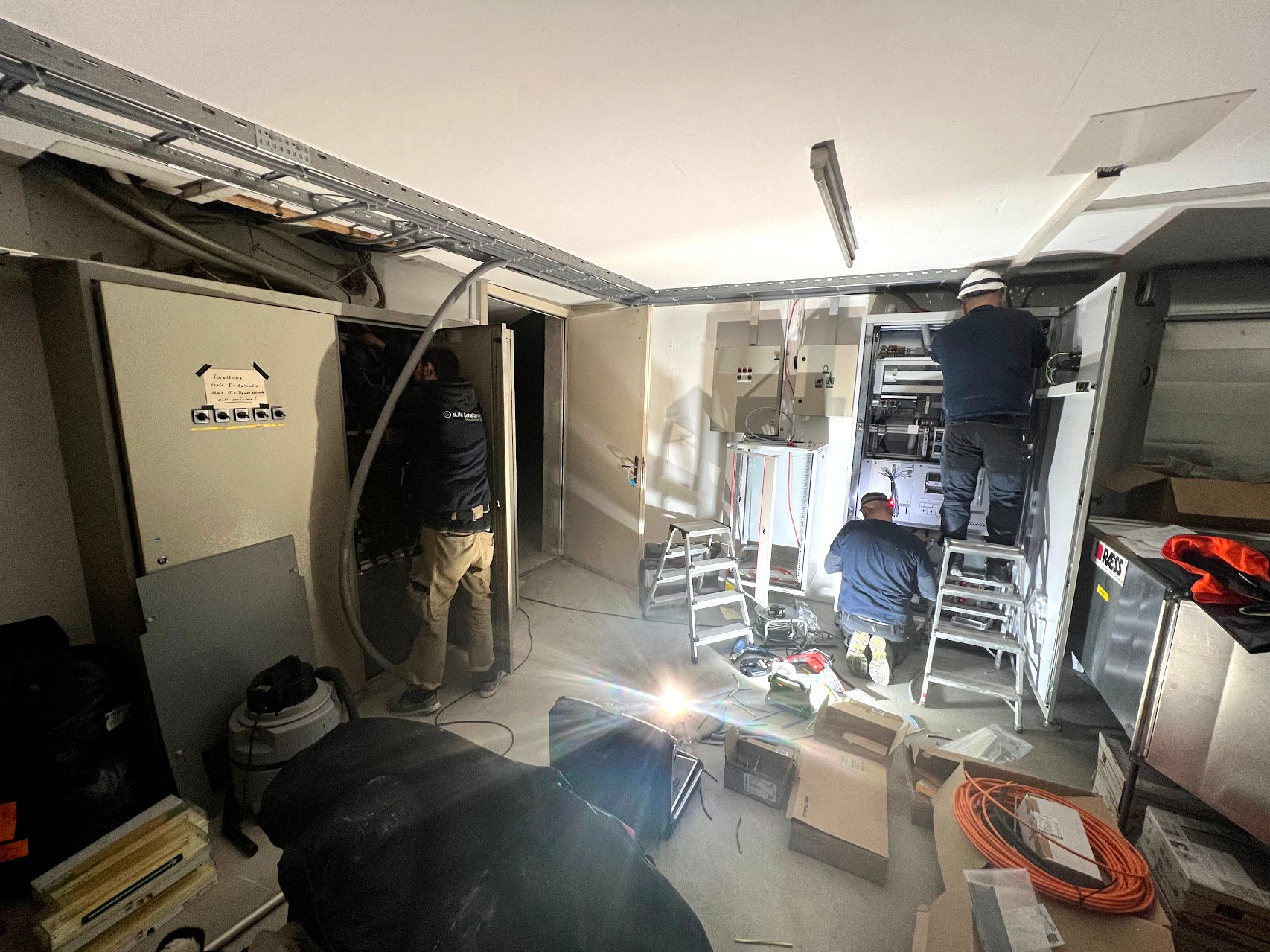 Zwei Techniker, die gerade Kabel verlegen, um die Ladestationen in einem Raum der Garage zu installieren
