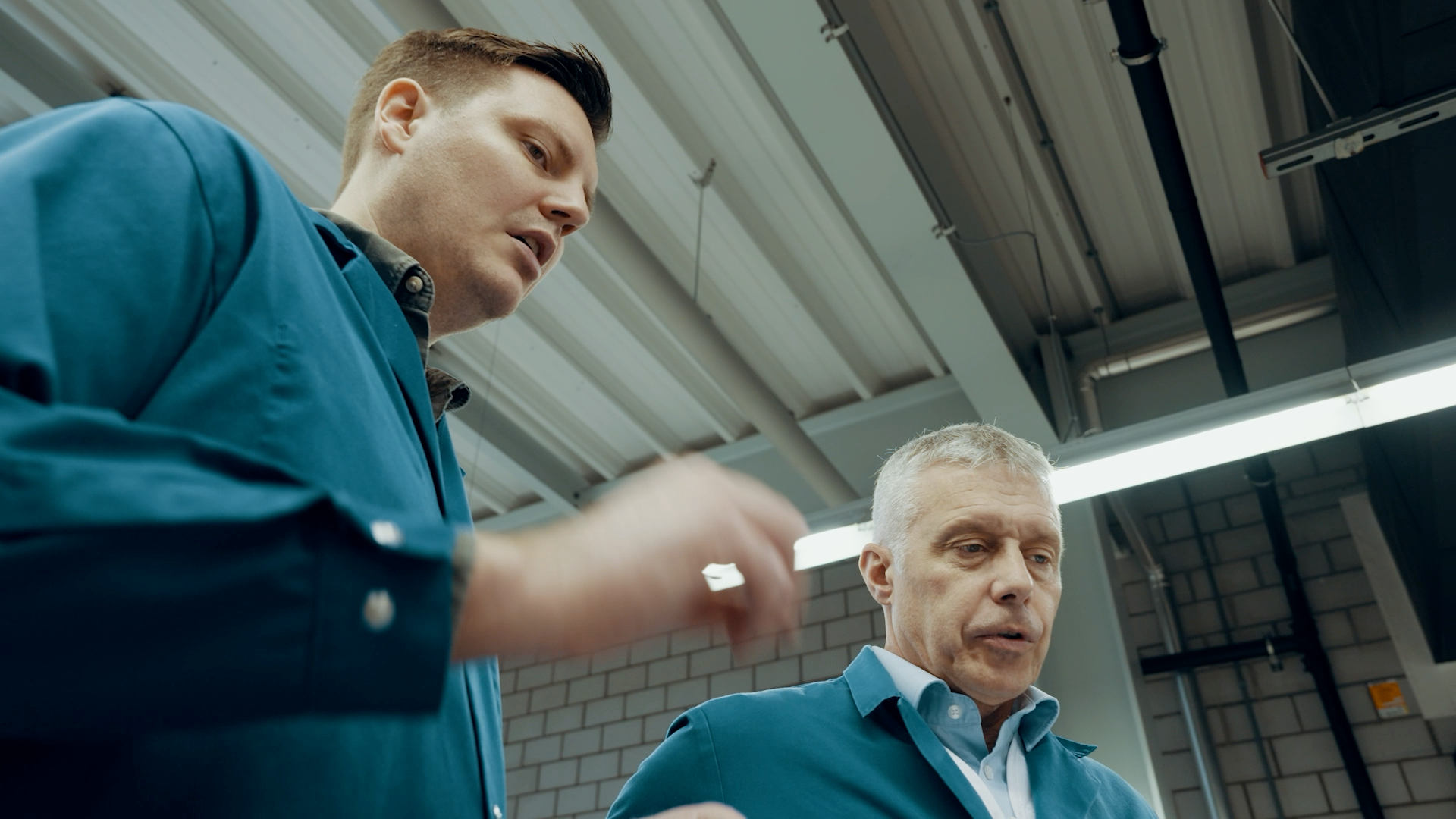 Zwei Mitarbeitende von Micarna besprechen einen Arbeitsprozess in einer Produktionshalle.